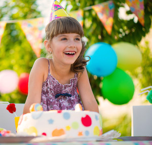 Young girl having a birthday party in the backyard with decorations and cake. 